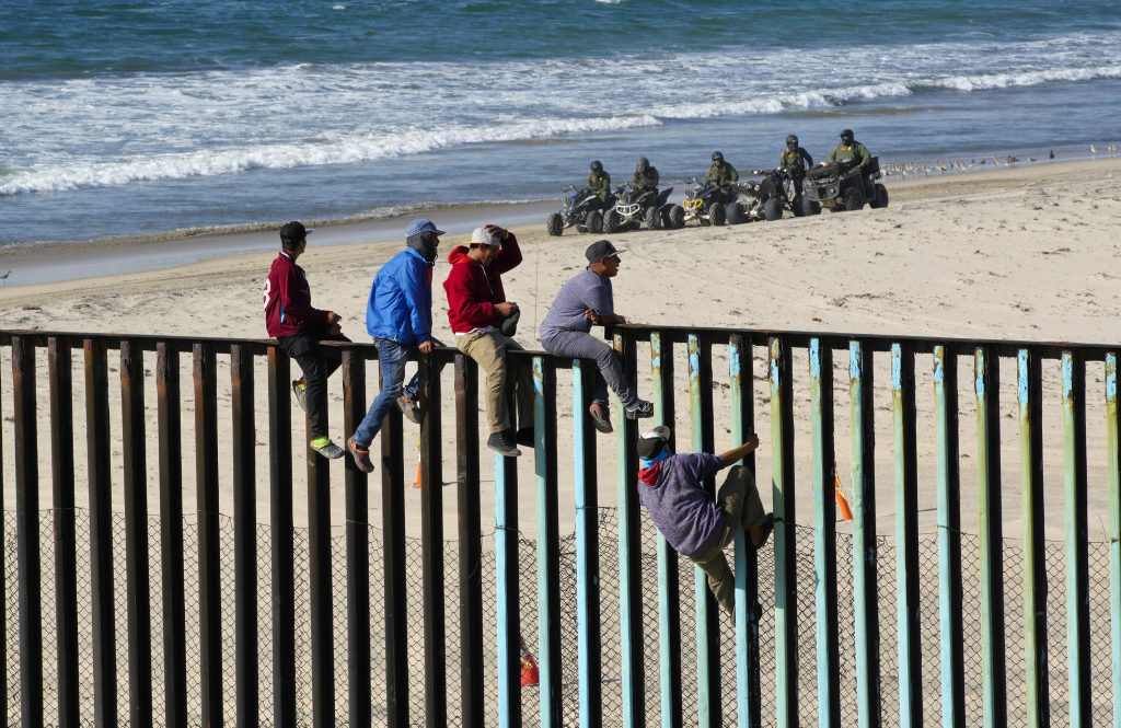 Migranți din America Centrală escaladează gardul care separă Mexic de SUA sub privirile poliției de frontieră Americană. Persoanele care apar în aceste fotografii nu au legătură cu personajele din articolul publicat de Libertatea. Foto: Hepta